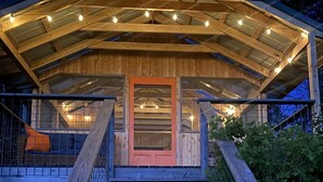 A wooden staircase leading to a covered entrance with a door, surrounded by a railing and a small seating area. - Gorgeous Finger Lakes Accommodation near Ithaca for Glamping in New York (Brooktondale)