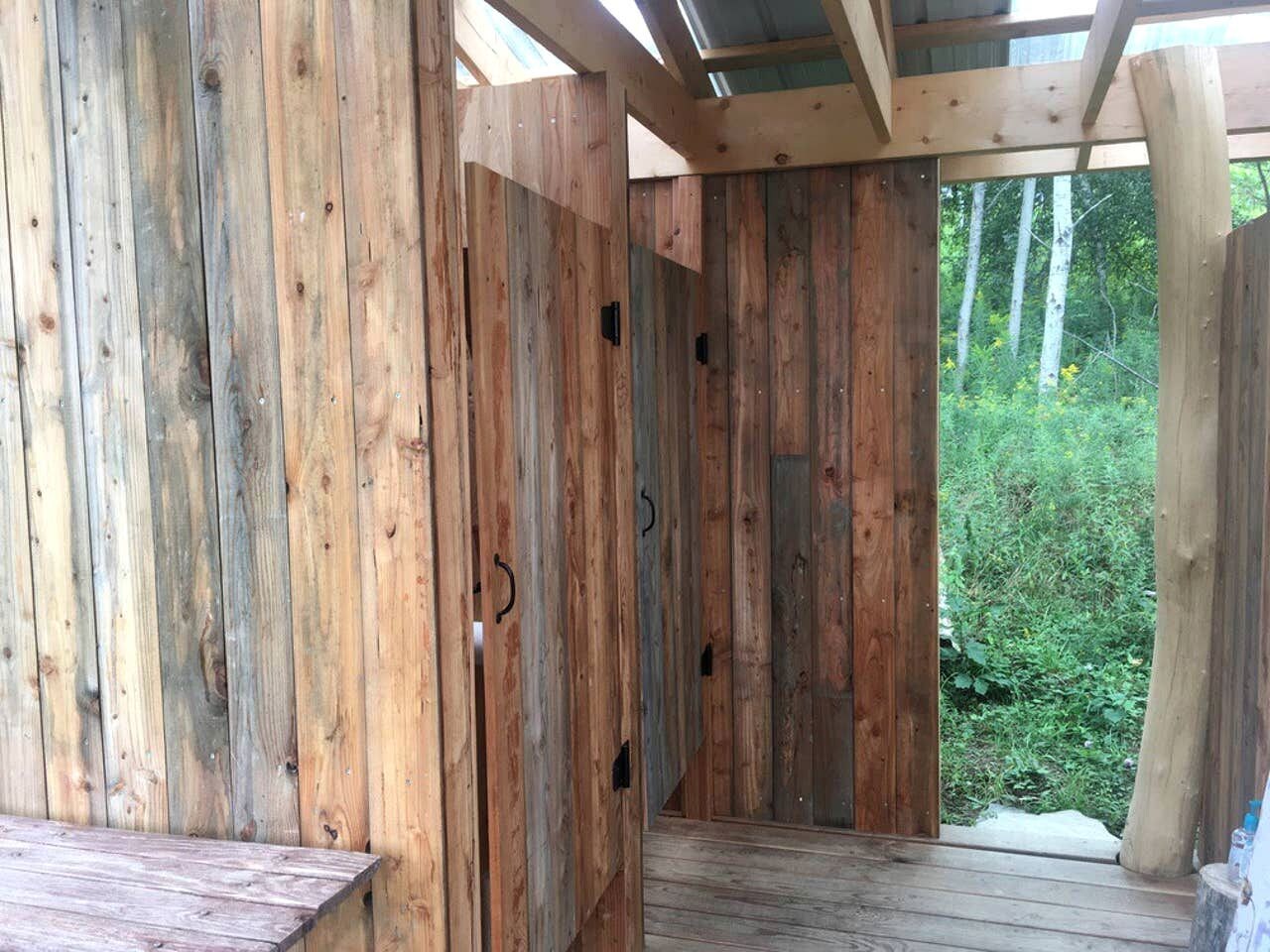 Una struttura in legno con panchina, tettoia e vista su spazi verdi.