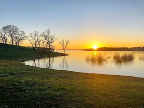 A serene lakeside view with trees and a clear sky.