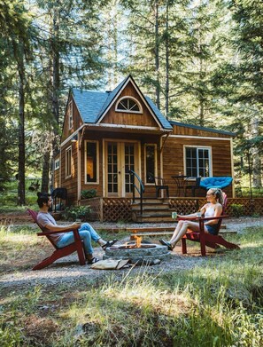 A cabin with a porch, a fire pit, and two people sitting on chairs. - Owl Creek Cabin Mountain Getaway near Ashland, Oregon (Ashland)