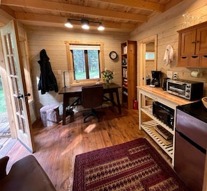 Een gezellig chaletinterieur met houten inrichting, een eettafel, een keuken met een magnetron en een raam.