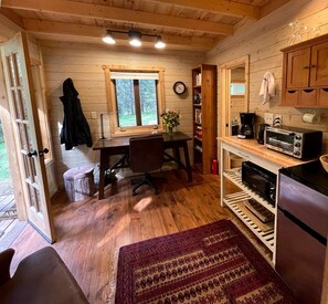 A cozy cabin interior with a wooden interior, a dining table, a kitchen area with a microwave, and a window. - Owl Creek Cabin Mountain Getaway near Ashland, Oregon (Ashland)