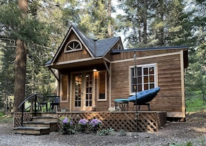 A wooden cabin with a porch, a chair, and a small table.