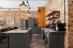 Een moderne keuken met een bakstenen muur, hangende lampen en een ingebouwde wasmachine.