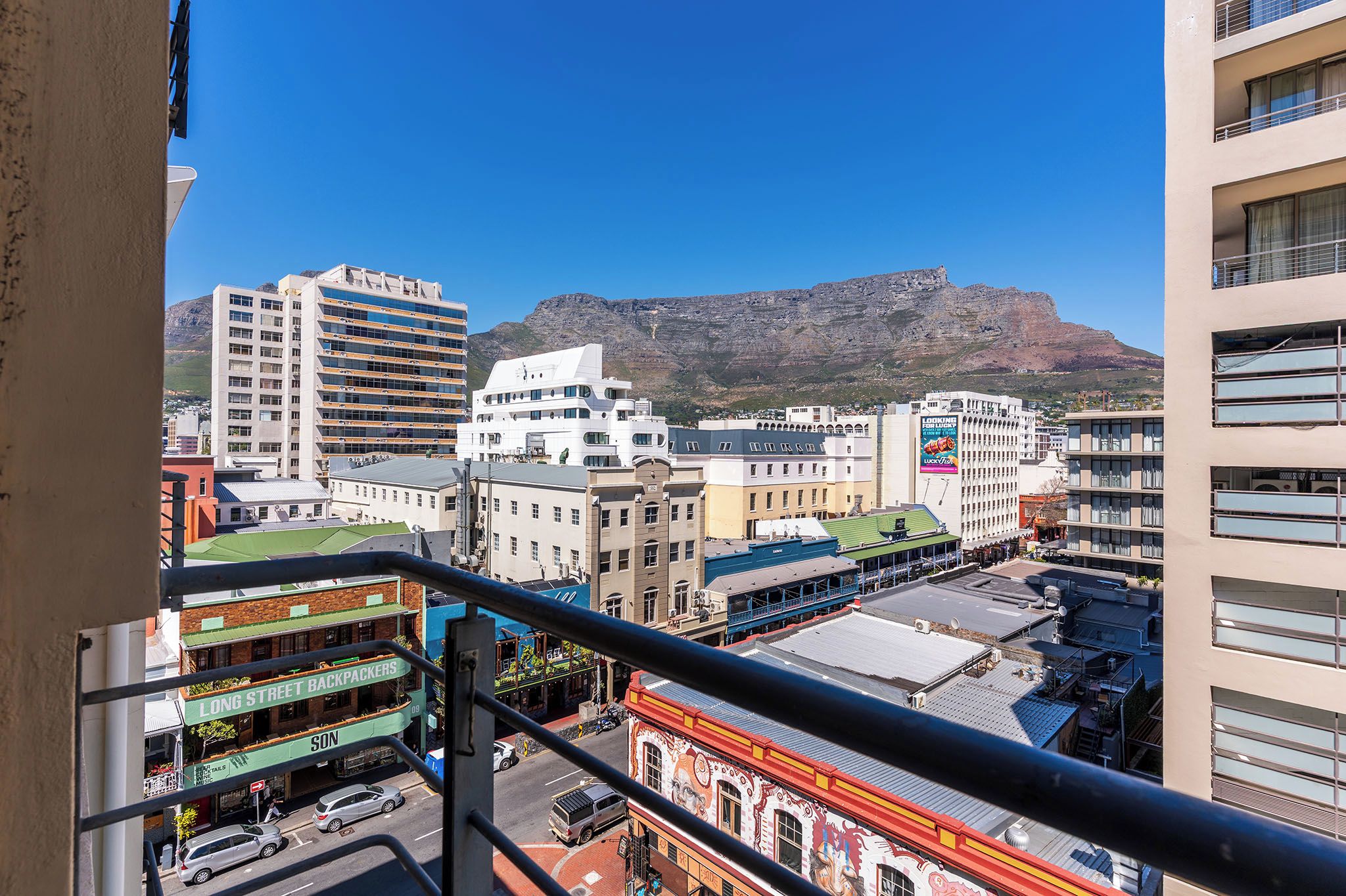A cityscape with buildings, a mountain in the background, and a street with cars.