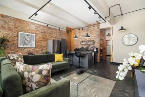 Een moderne woonkamer met een bank, salontafel en een keukenbar met barkrukken.