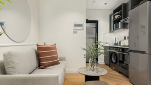 Una sala moderna con un sofá, una mesita de centro y una cocina con electrodomésticos.