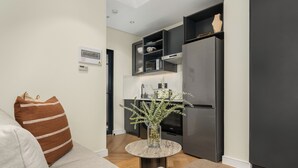 Una cocina moderna con refrigerador integrado, un pequeño comedor con mesa redonda y un sofá con cojín decorativo.