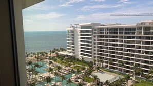 A high-rise hotel with multiple balconies overlooking a pool area and the ocean. - 3-bedroom condo in enchanting Cancún with fitness room, AC (Cancún)