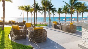 A beachside lounge with wicker furniture and yellow cushions, overlooking the ocean. - 3-bedroom condo in enchanting Cancún with fitness room, AC (Cancún)