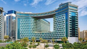 A modern hotel with a distinctive curved glass facade and a prominent overhanging structure.