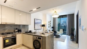 Una cocina moderna con lavadora y secadora integradas, un comedor con candelabro y vistas de la ciudad a través de amplias ventanas.