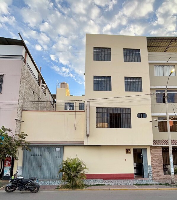 Un edificio de varios pisos con fachada plana, varias ventanas y una pequeña entrada.