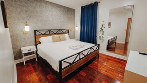 A modern bedroom with a wooden bed frame, a nightstand, a mirror, and a blue curtain.