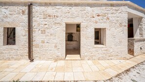 Ein Steingebäude mit einer mittleren Tür, zwei Fenstern und einem sichtbaren Rohr.