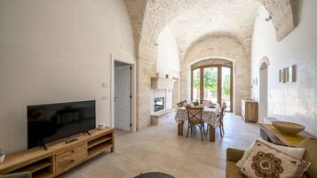 A spacious living area with a television, dining table, and seating.