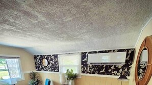 Un espai vital compacte amb zona de menjador, dues cadires blaves, taula petita, armari i mirall.