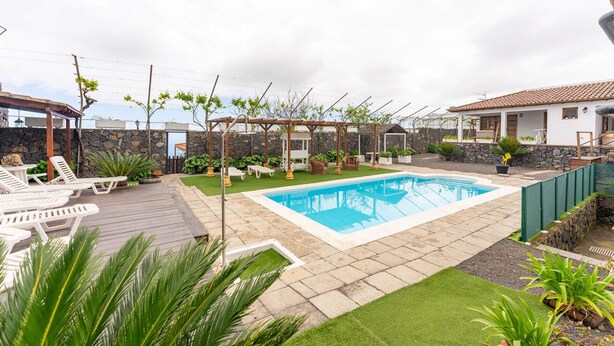 Un jardin avec une piscine, des chaises longues et une pergola.