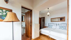 Une chambre avec deux lits, un plancher en bois, un grand miroir et une lampe suspendue.