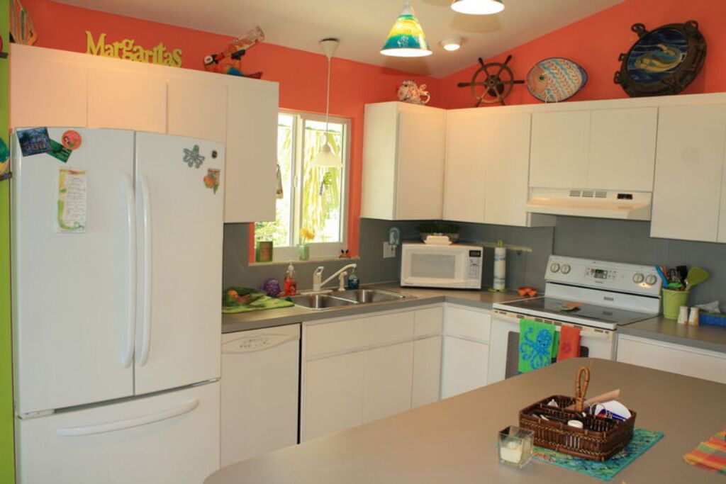 A compact kitchen with white cabinets, a refrigerator, a microwave, and a stove.