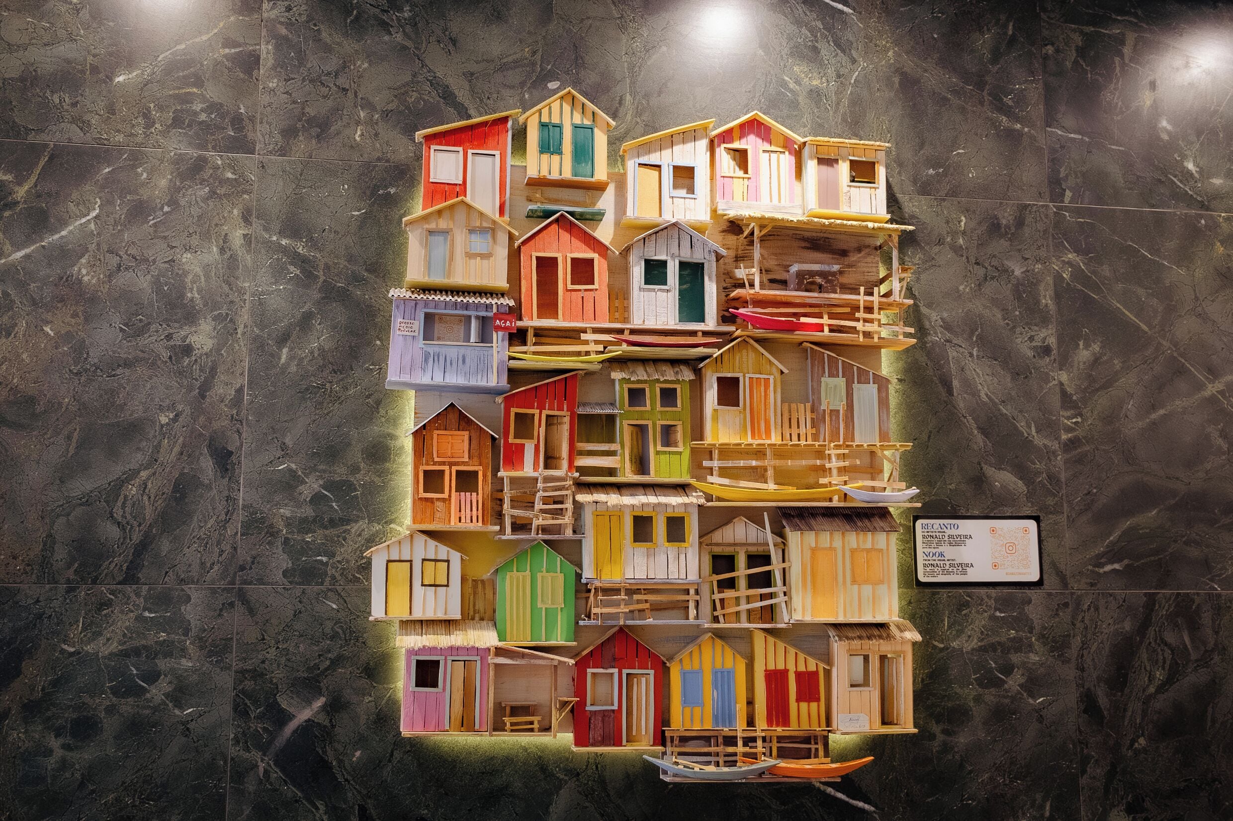 Un conjunto de coloridas casas de madera en miniatura expuestas sobre una pared de mármol.
