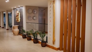 A hallway with potted plants, a wall-mounted shelf with books, and decorative plates. - Amazon Seasons Hotel (Belém)