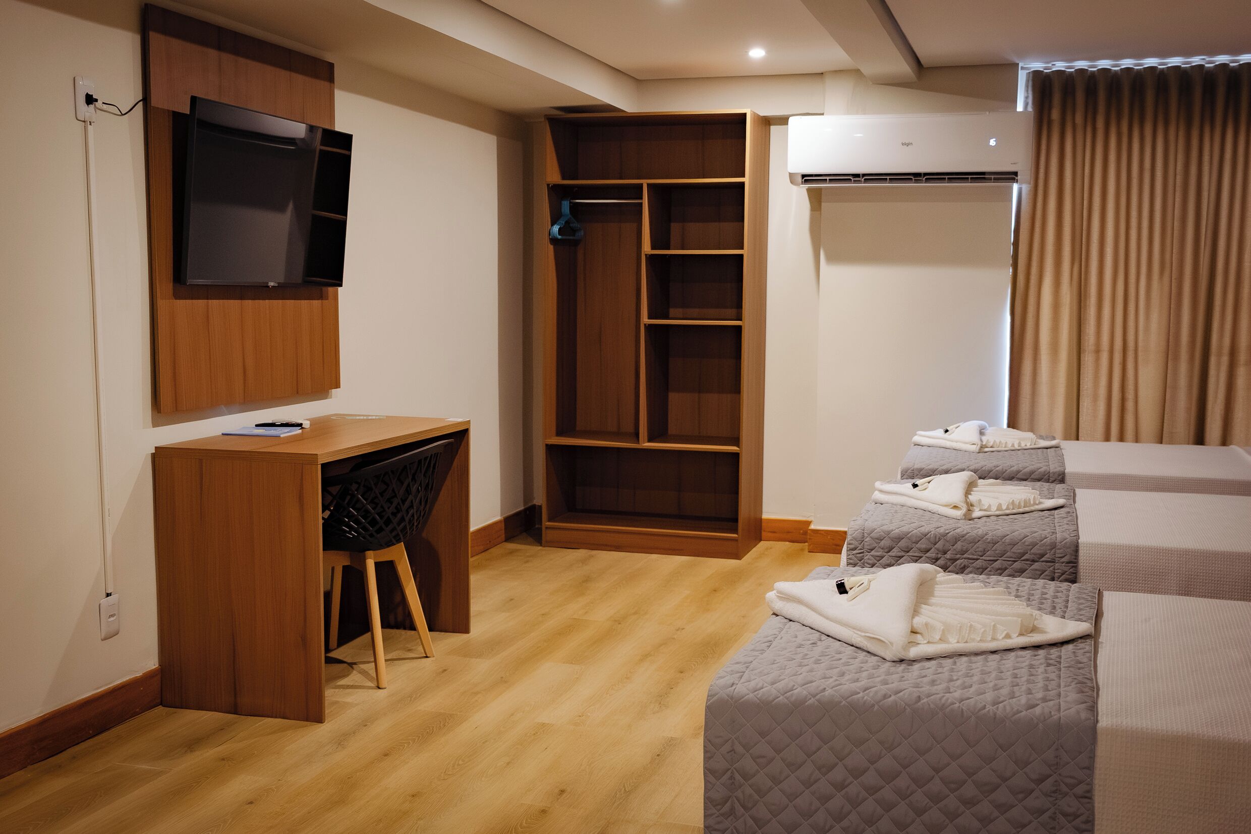 A hotel room with a desk, wardrobe, and two beds.