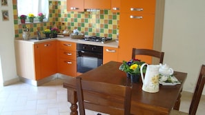Una cocina con gabinetes color naranja, una estufa y una mesa de comedor con sillas.