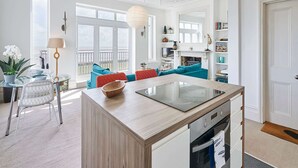 Une cuisine moderne dotée d’un îlot central, d’un four encastré et d’un coin repas avec une table ronde et des chaises.