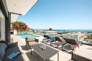 A rooftop terrace with a pool, lounge chairs, and a table with drinks.