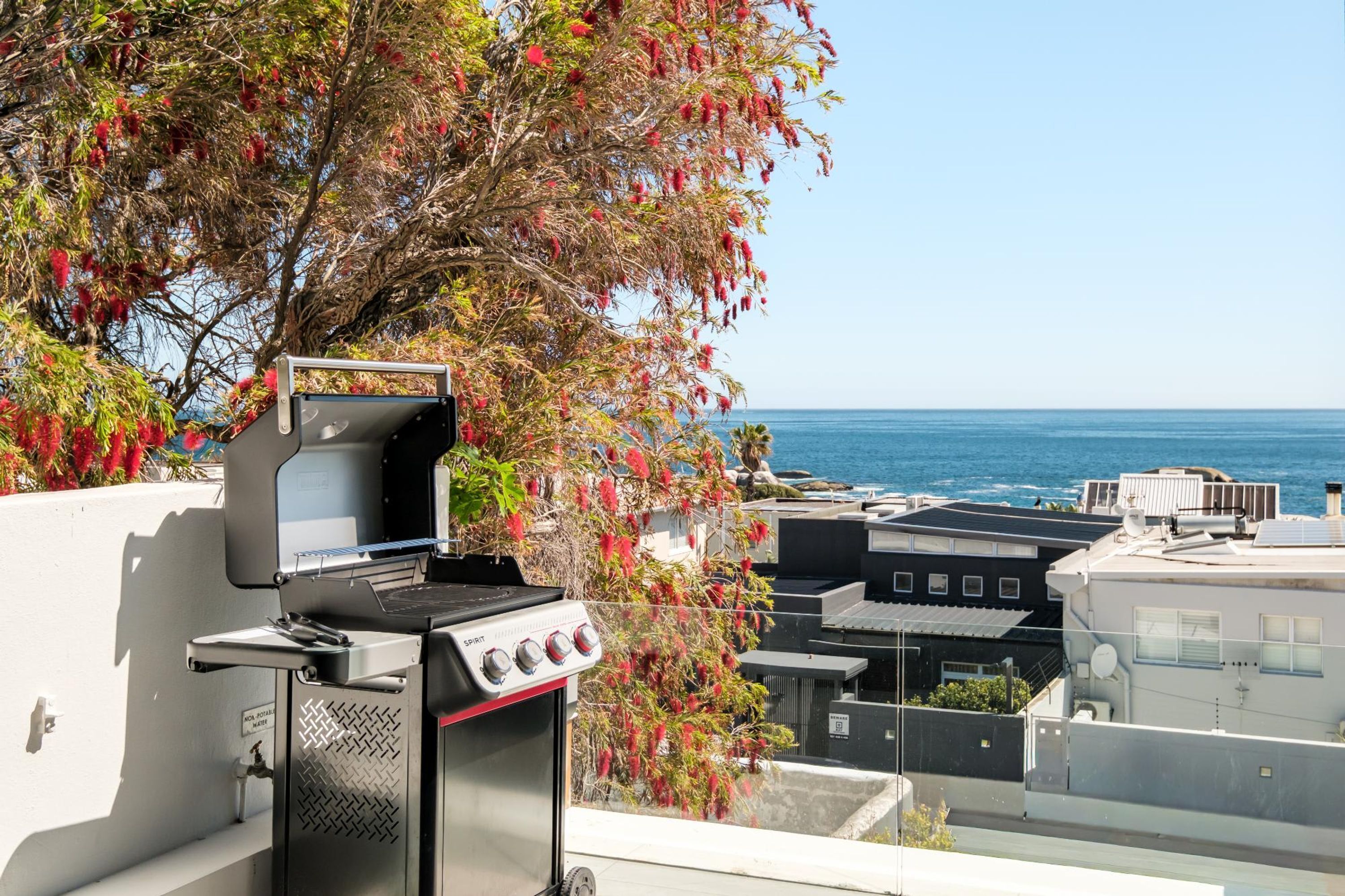 A rooftop barbecue grill with a view of the ocean.