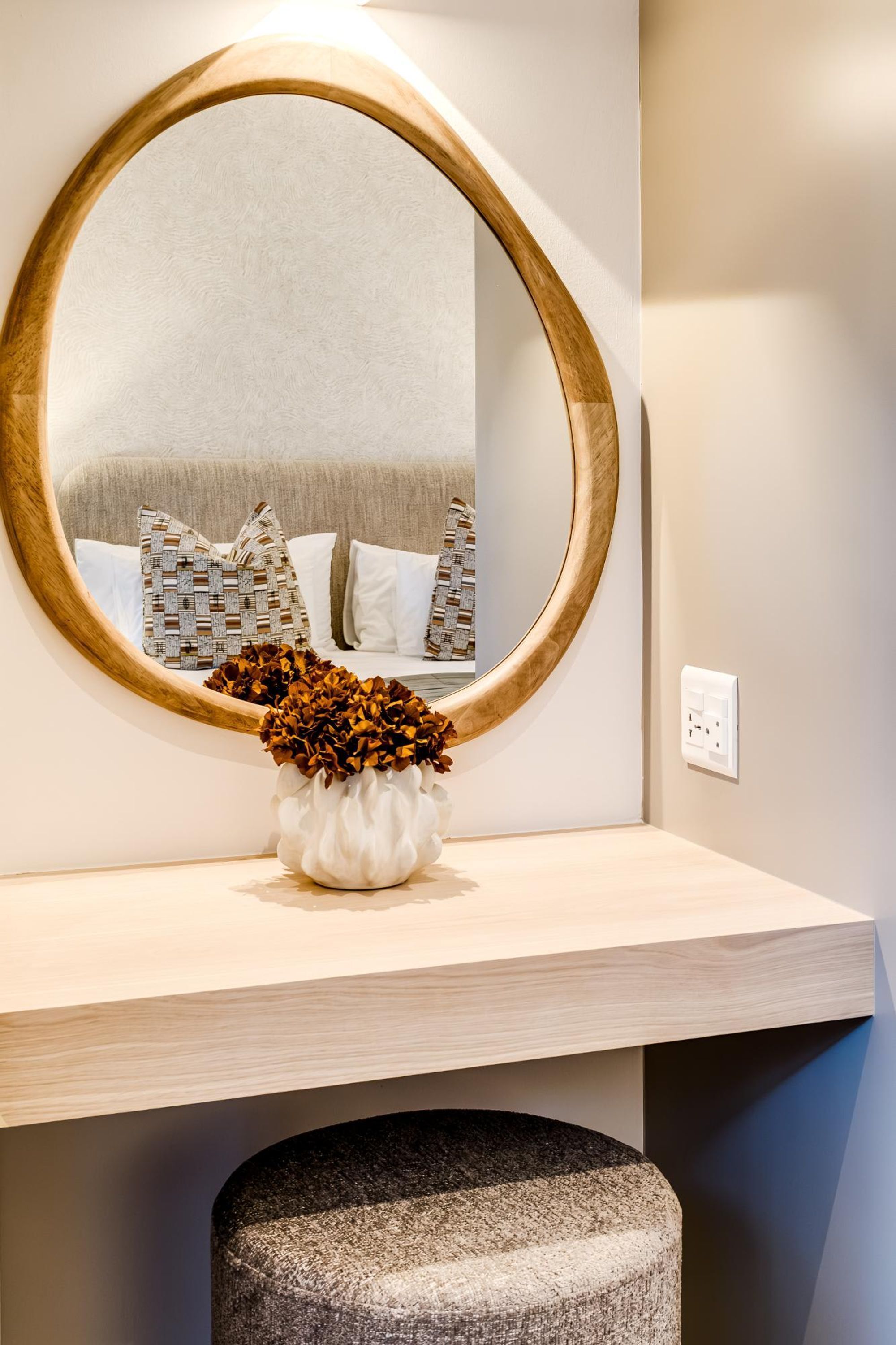 A round mirror with a wooden frame on a light-colored console table.