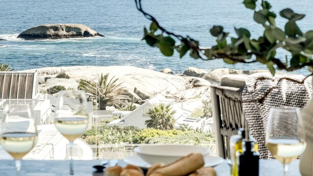 Une table à manger avec vue sur la mer, une bouteille et du pain.