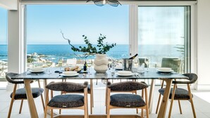 Un coin repas avec une table dressée pour quatre personnes, offrant une vue imprenable sur l’océan.