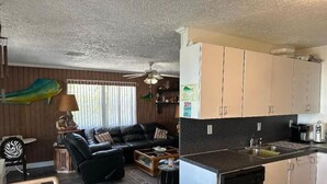 A compact living space with a kitchenette, a sofa, a dining table, and a ceiling fan. - Cozy 2 Bedroom 1 Bath Canal Front Home On Ramrod Key (Ramrod Key)