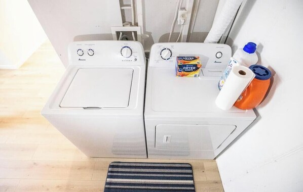 A laundry area with two white washing machines, a dryer, and laundry supplies. - Charming 3-bedroom house in Wakefield with AC (Wakefield)
