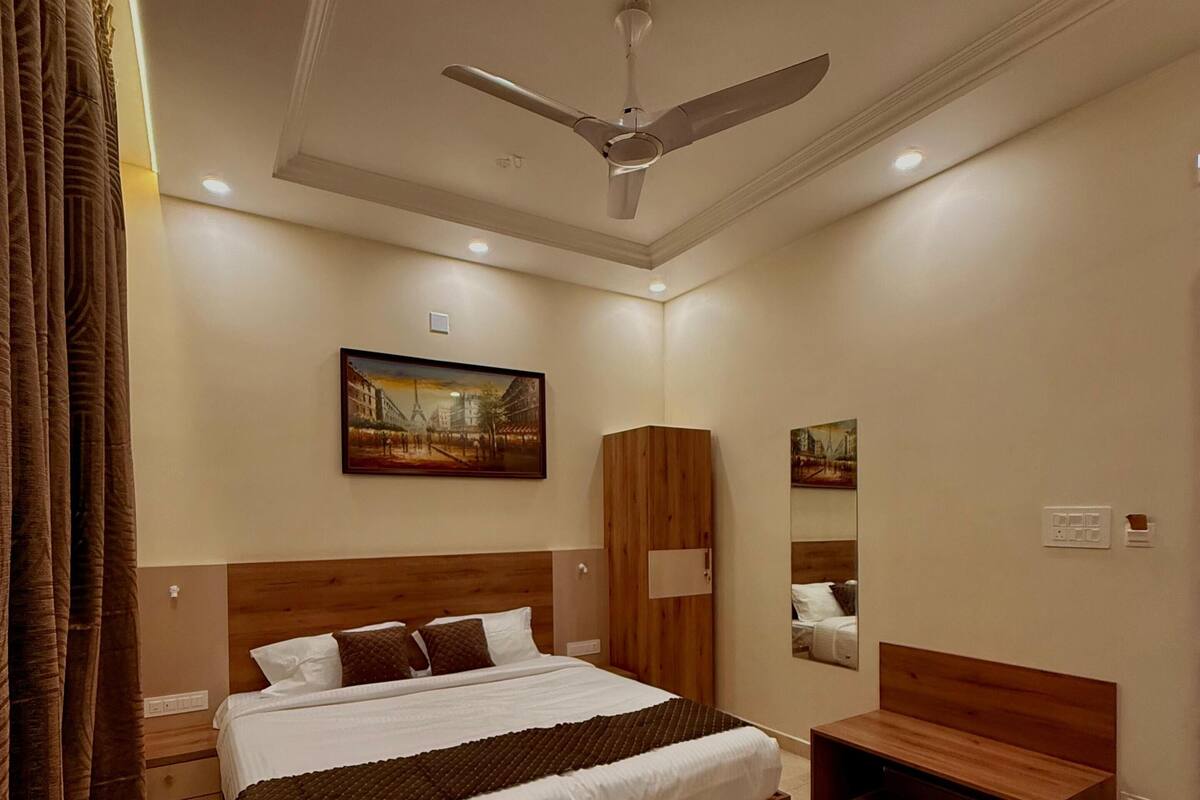 Ein modernes Schlafzimmer mit einem großen Bett, einer Holzbank, einem Deckenventilator und Kunstwerken an den Wänden.