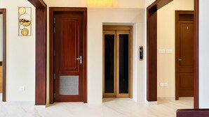 A hallway with a wooden door, a glass door, and a light fixture above. - Coastal Echoes Inn (Kochi)