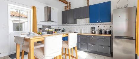 A kitchen with a wooden table, two chairs, a refrigerator, and blue cabinets.