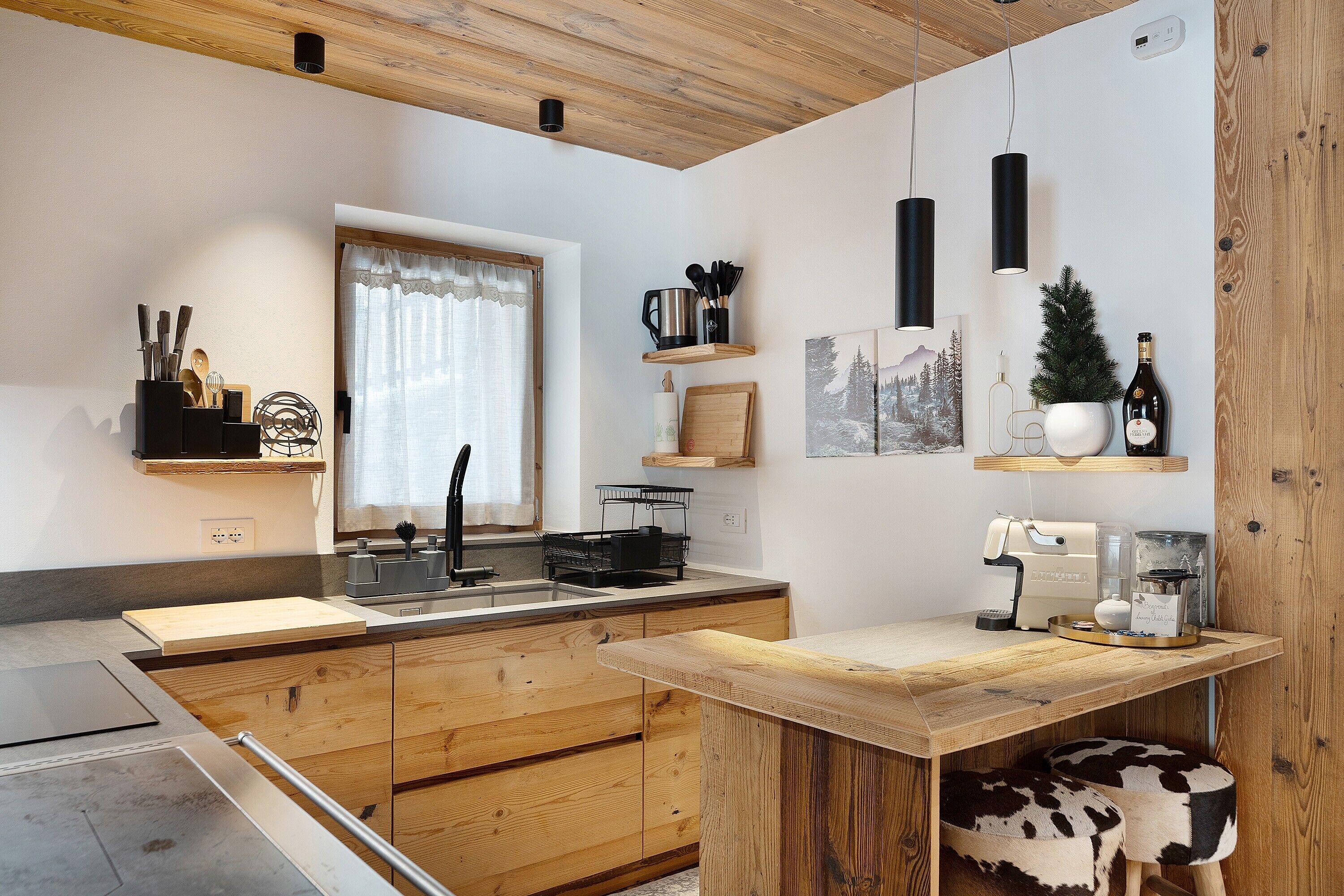Eine moderne Küche mit Holzschränken, einem eingebauten Herd und einer Kaffeemaschine.