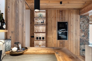 A kitchen with wooden walls, a stone accent wall, and a built-in microwave.