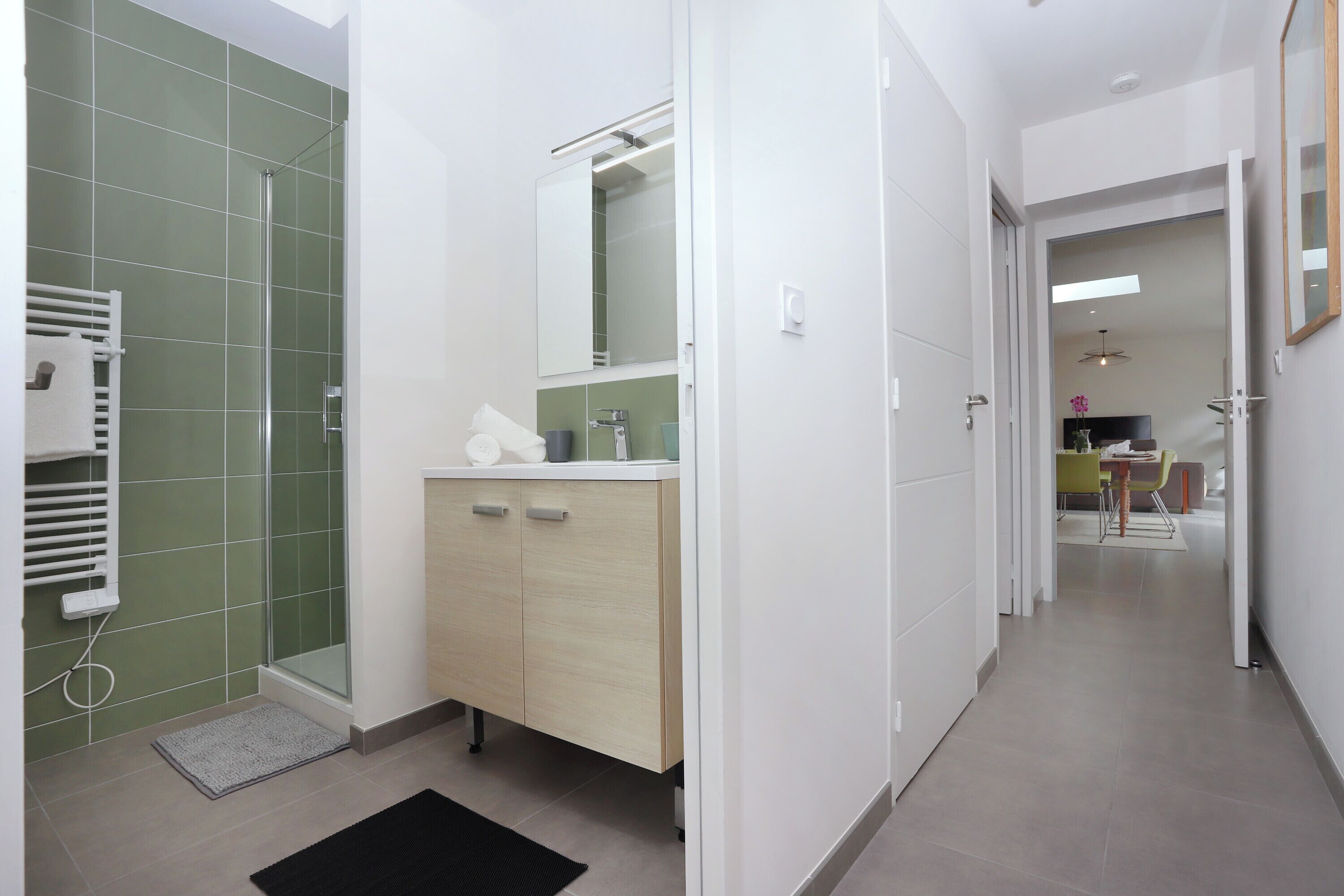 Une salle de bain moderne avec une douche, un lavabo et un miroir.