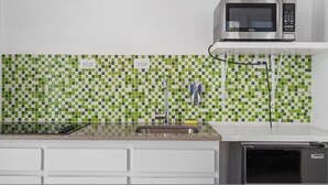 A kitchen with a microwave, sink, and tiled backsplash. - Near the Water Shared Pool Pets Permitted (San Juan)