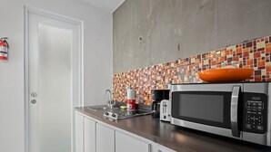 A modern kitchen with a stainless steel microwave, a coffee maker, and a bowl on the counter.