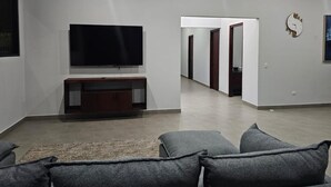 A modern living room with a flat-screen TV, grey sofas, and a wooden entertainment unit. - Palmas - Infinity Pool House - Bagaces La Fortuna. (Provincia de Guanacaste)