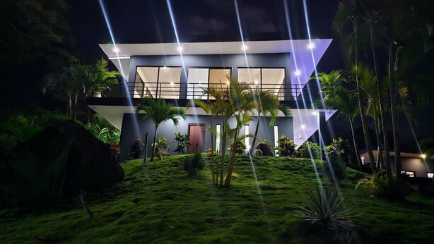 A modern house with a flat roof, large windows, and a well-lit exterior at night. - Palmas - Infinity Pool House - Bagaces La Fortuna. (Provincia de Guanacaste)