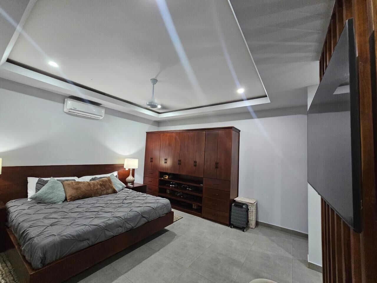 Ein Schlafzimmer mit Bett, Kleiderschrank, Fernseher und Deckenventilator.
