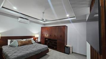 Ein Schlafzimmer mit Bett, Kleiderschrank, Fernseher und Deckenventilator.