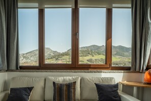 A room with a large window, a sofa, and a small table with a vase. - Holiday Home 'Casa Carmen' with Mountain Views (Parres)