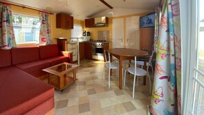 A compact living space with a sofa, a small table, a kitchenette, and a dining area. - Lovely home at park de Kniphorst (Anloo)